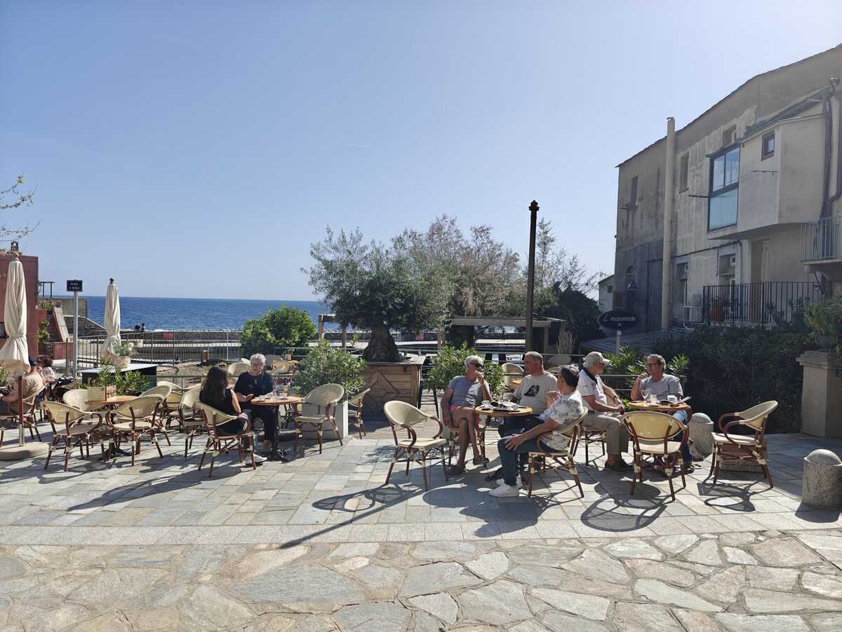 Un serveur s’affaire à dresser les tables sur la terrasse d’un restaurant corse.